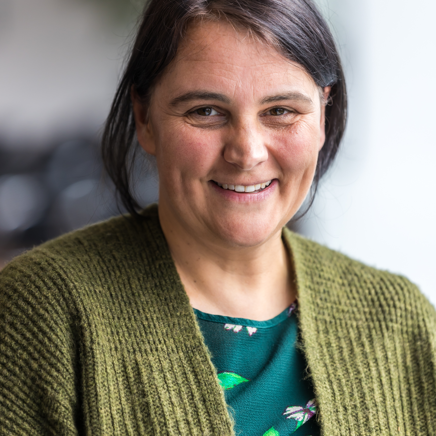 Portrait einer Frau mit dunklen, langen Haaren, zu einem Zopf zusammengebunden