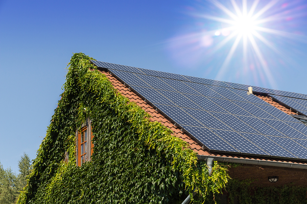 Wohnhaus mit PV-Anlage auf dem Dach, auf welche die Sonne scheint