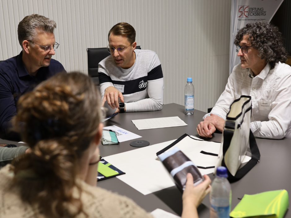 Vier Personen sitzen an einem Tisch und reden miteinander während sie ein neues Produkt testen