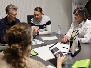 Vier Personen sitzen an einem Tisch und reden miteinander während sie ein neues Produkt testen