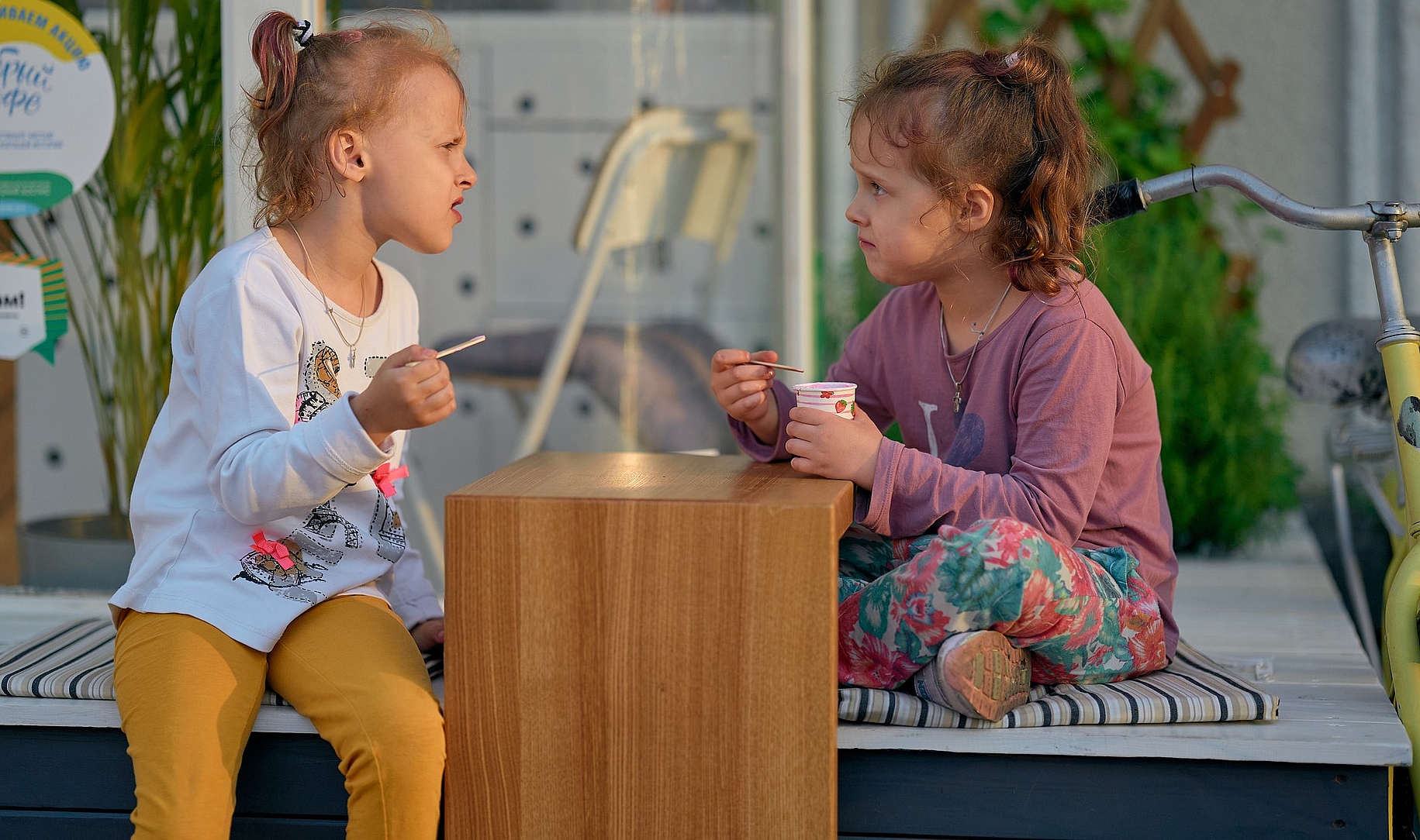 zwei Mädchen sitzen an einem Tisch und essen Eis