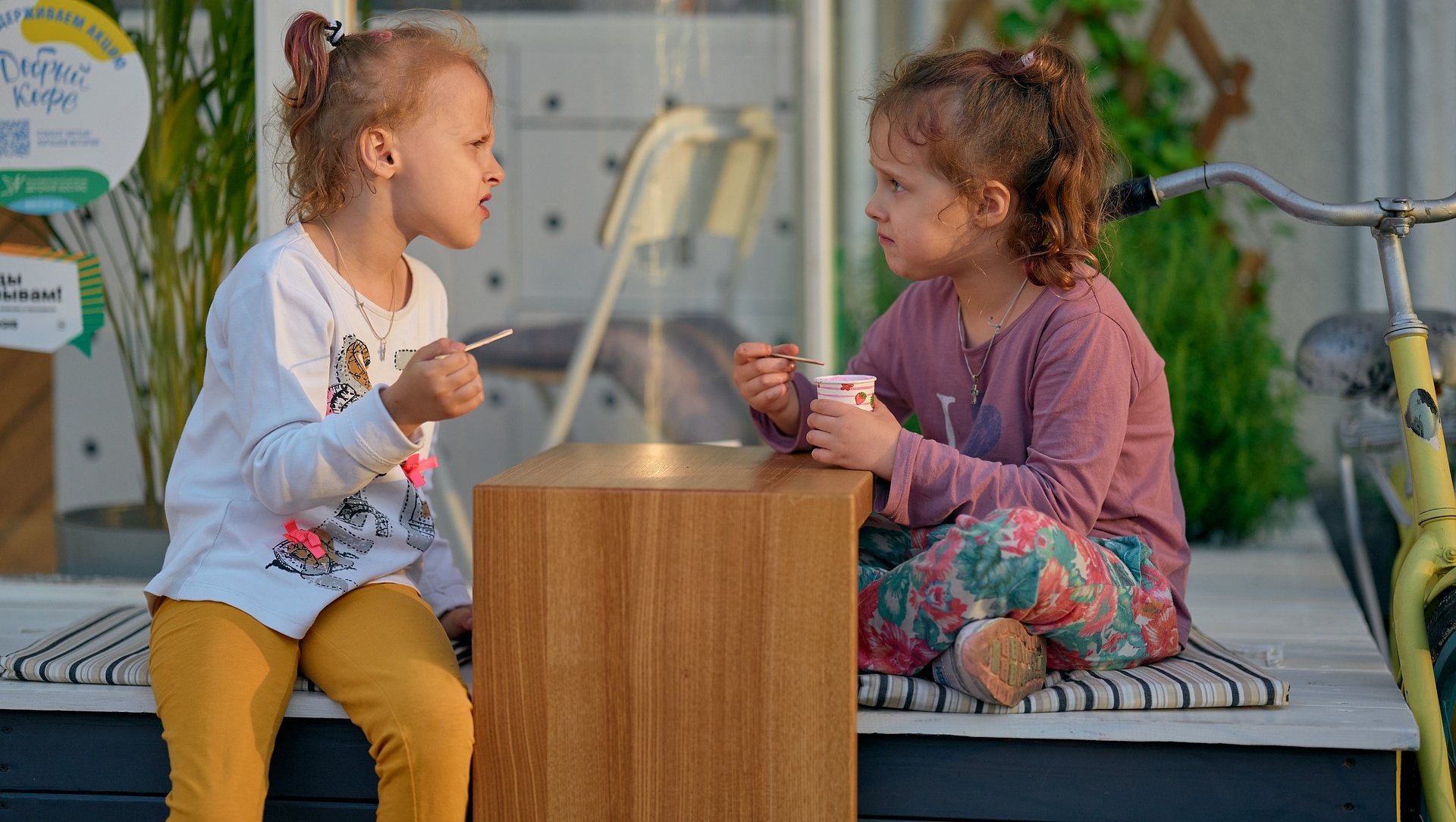 zwei Mädchen sitzen an einem Tisch und essen Eis