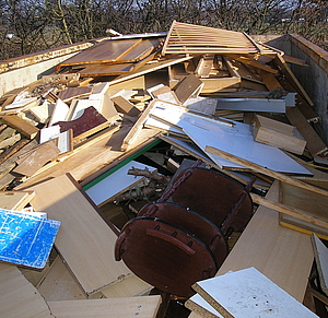 Container, der befüllt ist mit verschiedenen Gegenständen aus Holz, wie z. B. Lattenroste, Holzmöbel, Holzplatten, Holzregale.