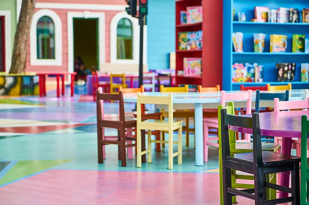Raum eines Kindergartens mit bunten Kinderstühlen und Regalen
