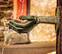 Brunnenausschnitt, patinierte Metallhand Patinierte Metallhand von der Seite, von oben ein Wasserstrahl, der aus der Hand dann weiter nach unten läuft - als Bildausschnitt eines Brunnens