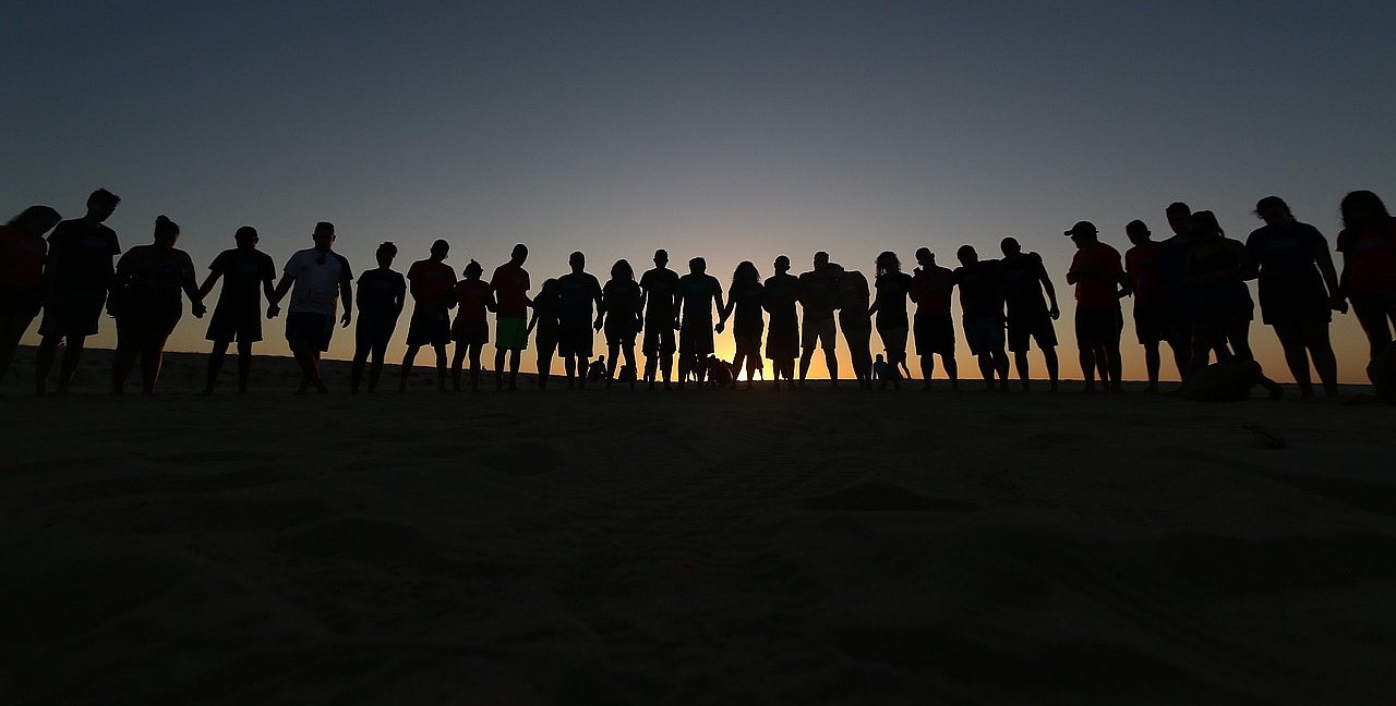 Viele Menschenumrisse vor einem Sonnenuntergang
