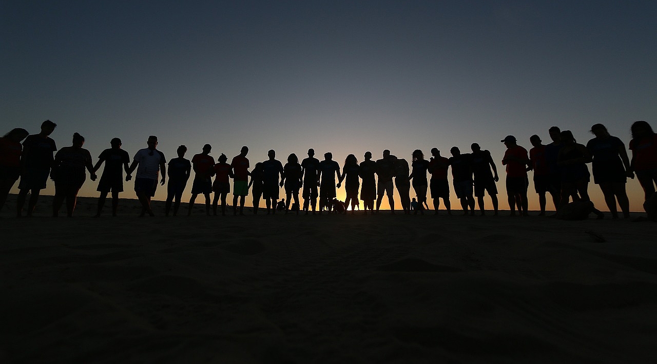 Viele Menschenumrisse vor einem Sonnenuntergang