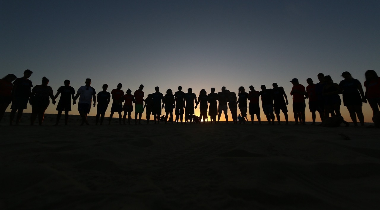 Viele Menschenumrisse vor einem Sonnenuntergang