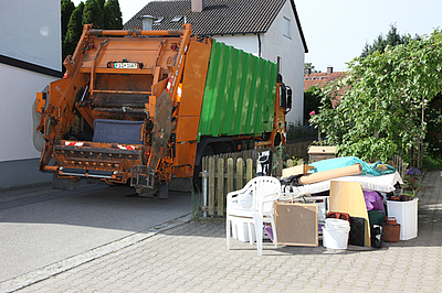 Müllauto und Sperrmüll wie Plastikstühle, Matratzen