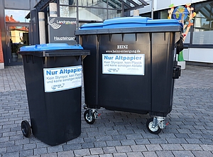 Papierbehälter in den Größen 240 l und 1.100 l mit schwarzem Korpus und blauem Deckel.