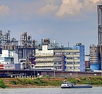 Industriewerk mit Raffinerie, im Vordergrund ein Fluss mit Lastenkahn