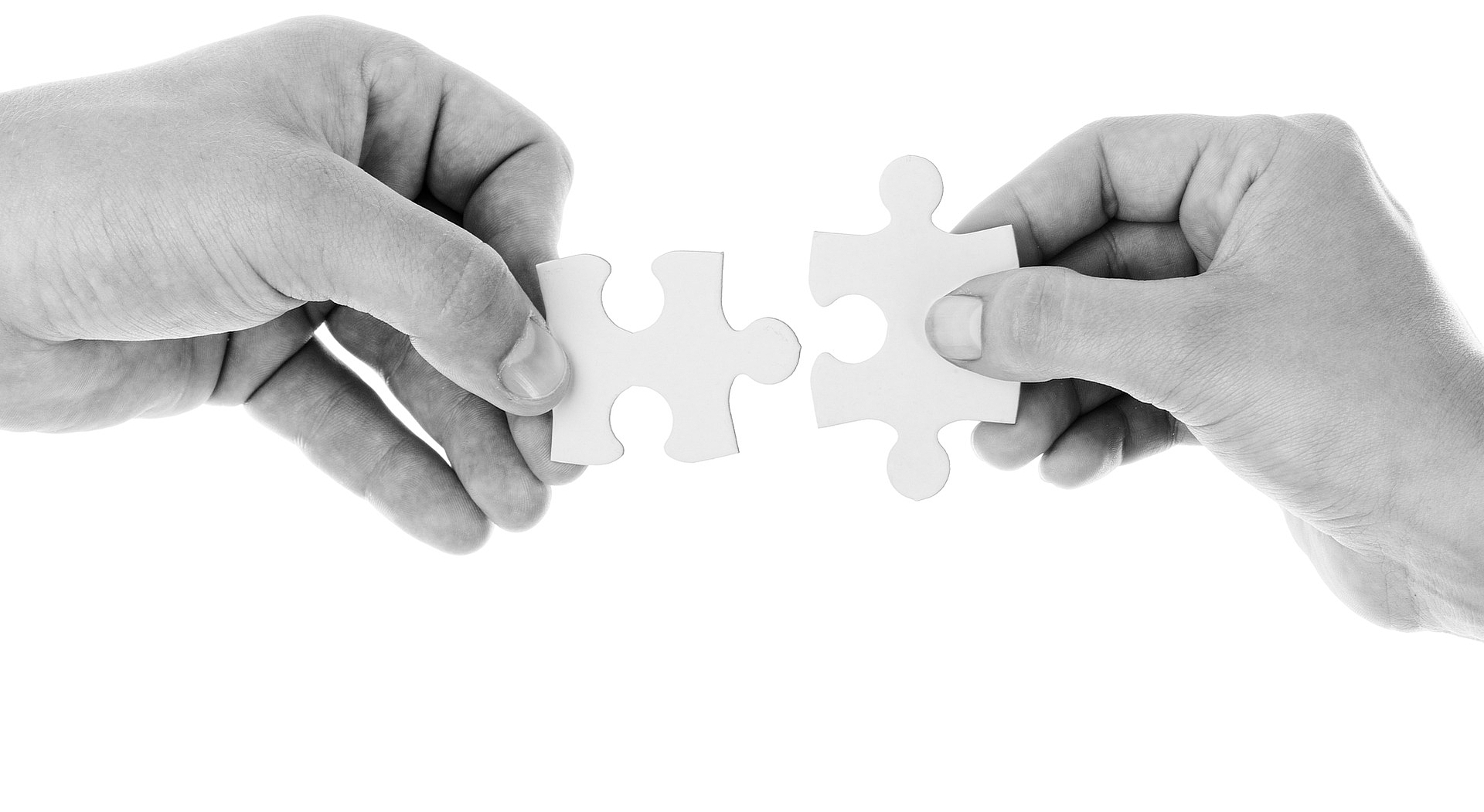 Zwei Hände die zwei Puzzlestücke zusammenfügen