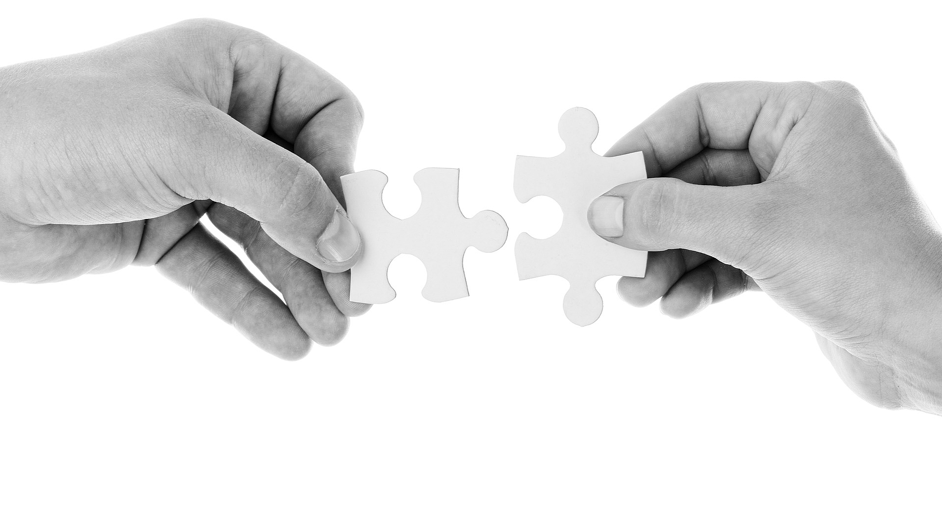 Zwei Hände die zwei Puzzlestücke zusammenfügen