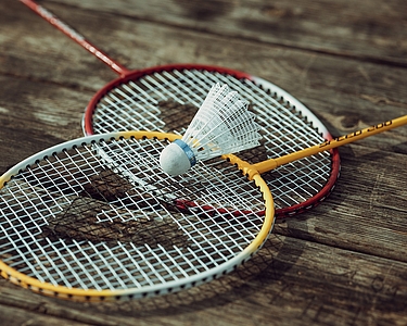 zwei Badmintonschläger liegen übereinander, auf ihnen liegt ein Federball