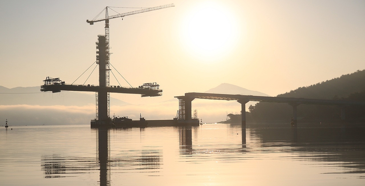 Brückenbau über Wasser mit Bergen im Hintergrund