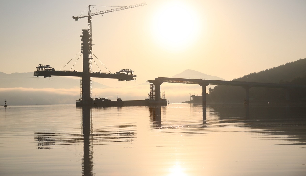 Brückenbau über Wasser mit Bergen im Hintergrund