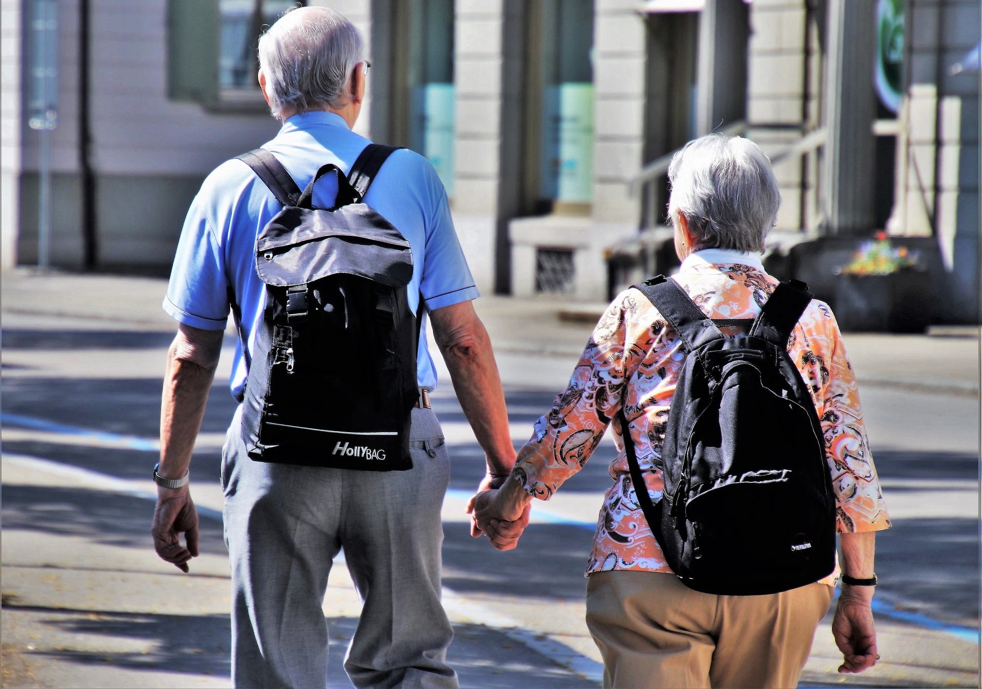 Älterer Herr und ältere Dame die Händchenhaltend durch die Stadt laufen 