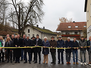 : Ein gemeinsamer Schnitt zur offiziellen Freigabe der Brücke: (Personen mit Schere von links) Pfarrer Michel Seifert, Andreas Maierhofer (2. Bürgermeister Gemeinde Polling), Landrat Max Heimerl, stv. Landrätin Ilse Preisinger-Sontag, Bürgermeistersprecher Thomas Einwang, Karl-Heinz Stocker von der Polizei Mühldorf, Peter Weber (IGL, PUTZ + PARTNER mbB Beratende Ingenieure), Robert Martinez (Tiefbauleiter Landratsamt Mühldorf a. Inn), Martin Gebler (Ingenieurbüro Behringer & Partner mbB), Martin Höpp (Fa. Hagn Umwelttechnik GmbH)