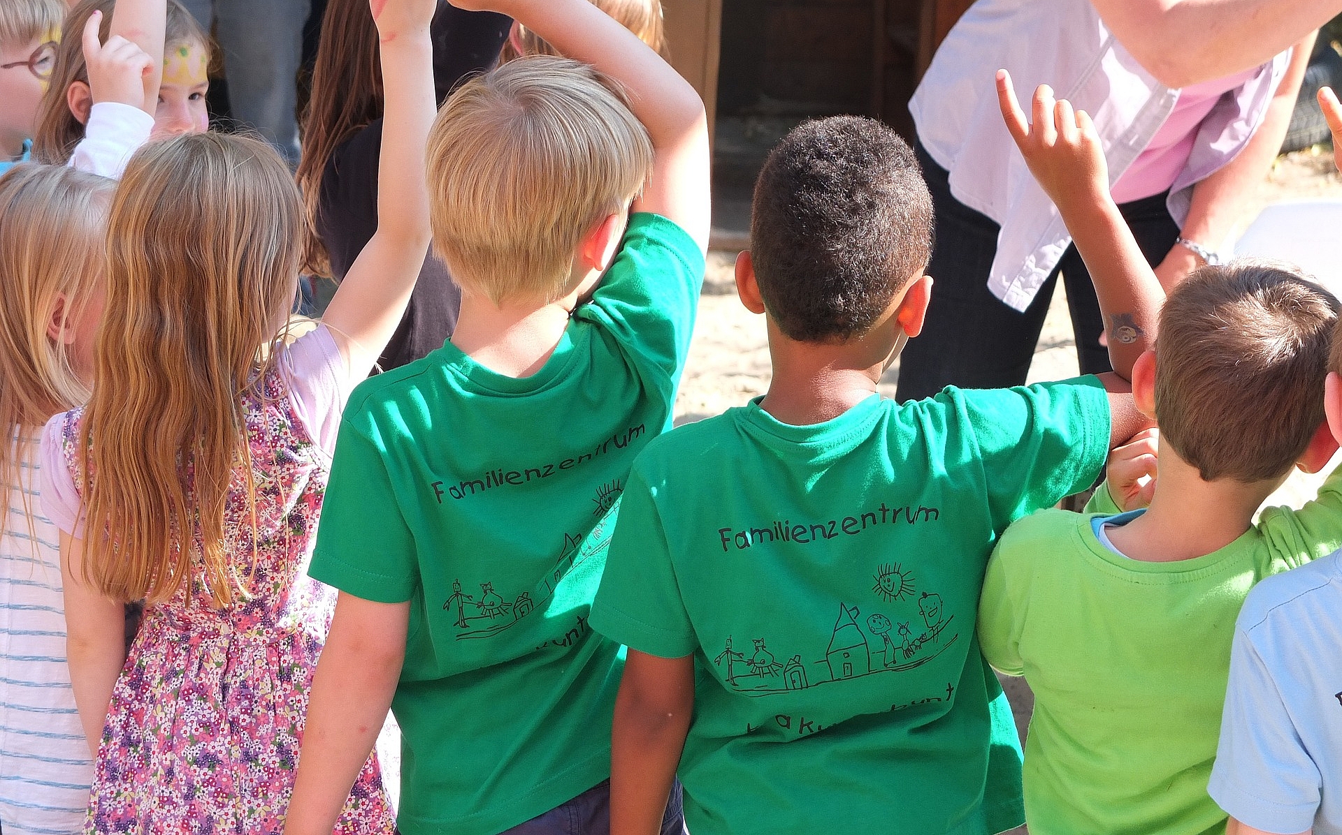 Kinder stehen mit dem Rücken zum Betrachter in einer Reihe