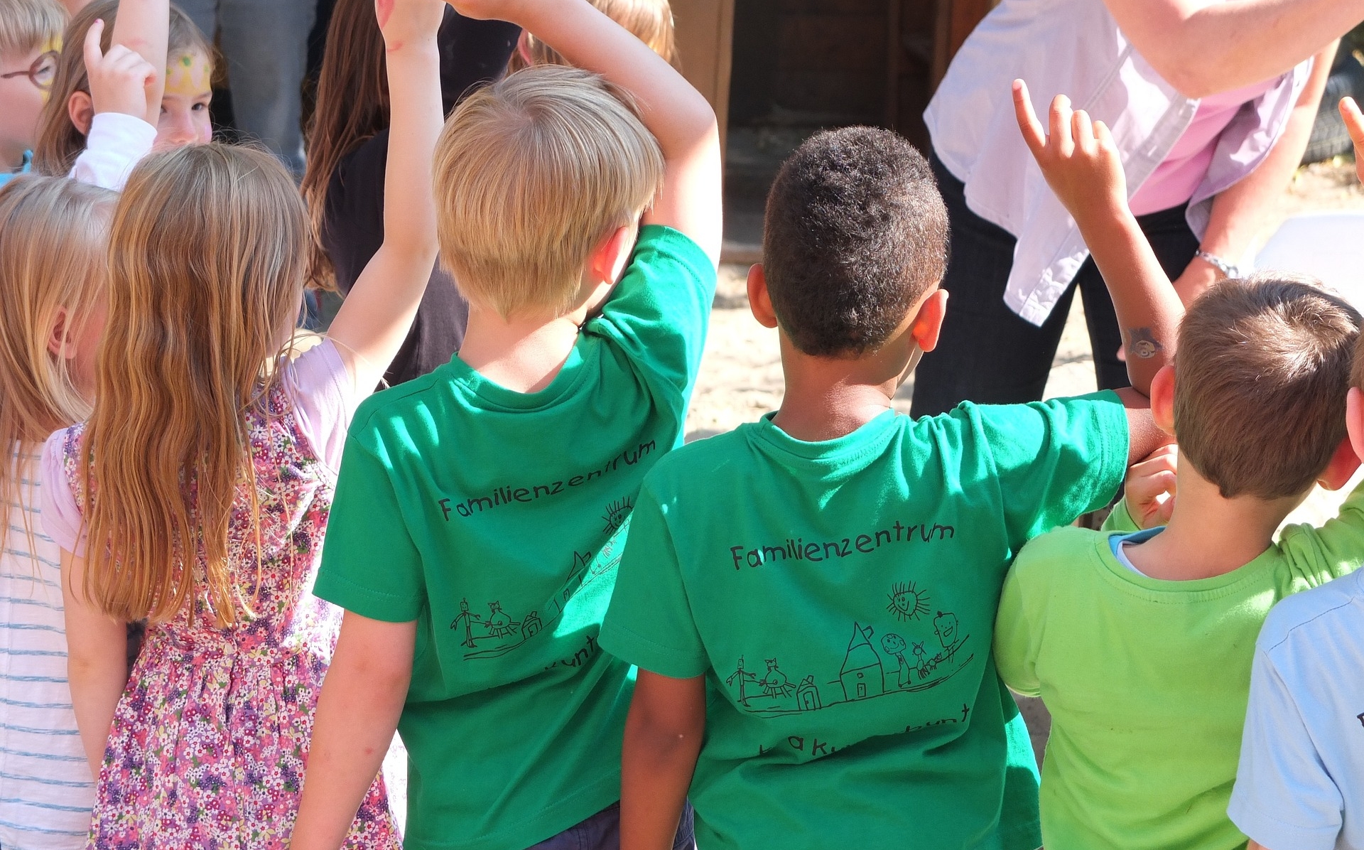 Kinder stehen mit dem Rücken zum Betrachter in einer Reihe