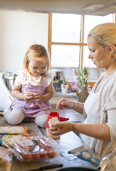 Mutter und Kleinkind in der Küche, Kind sitzt auf Arbeitsplatte