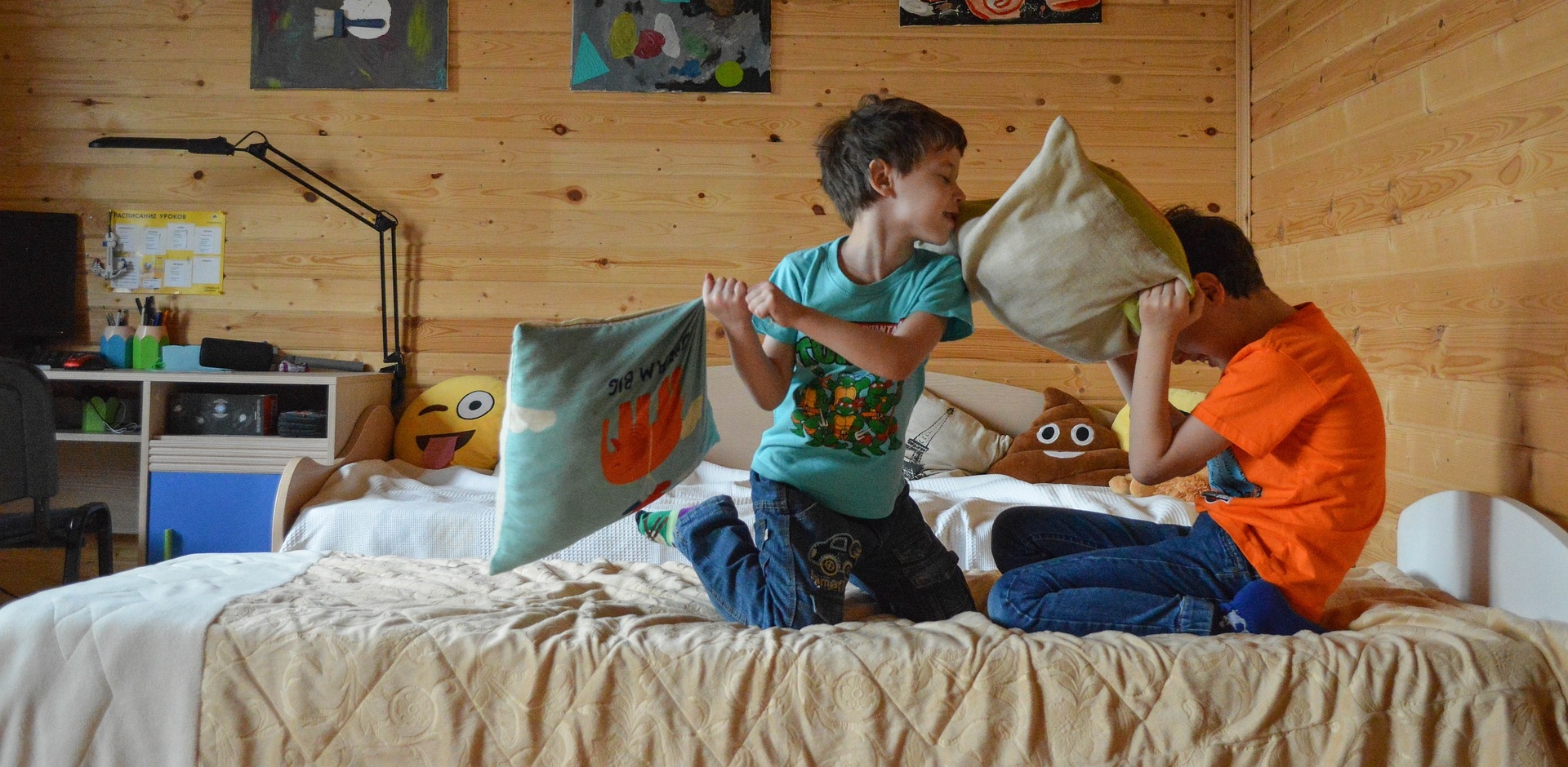 zwei Jungen sitzen auf einem Bett und machen eine Kissenschlacht