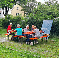 Mehrere ältere Personen sitzen auf Bierbänken