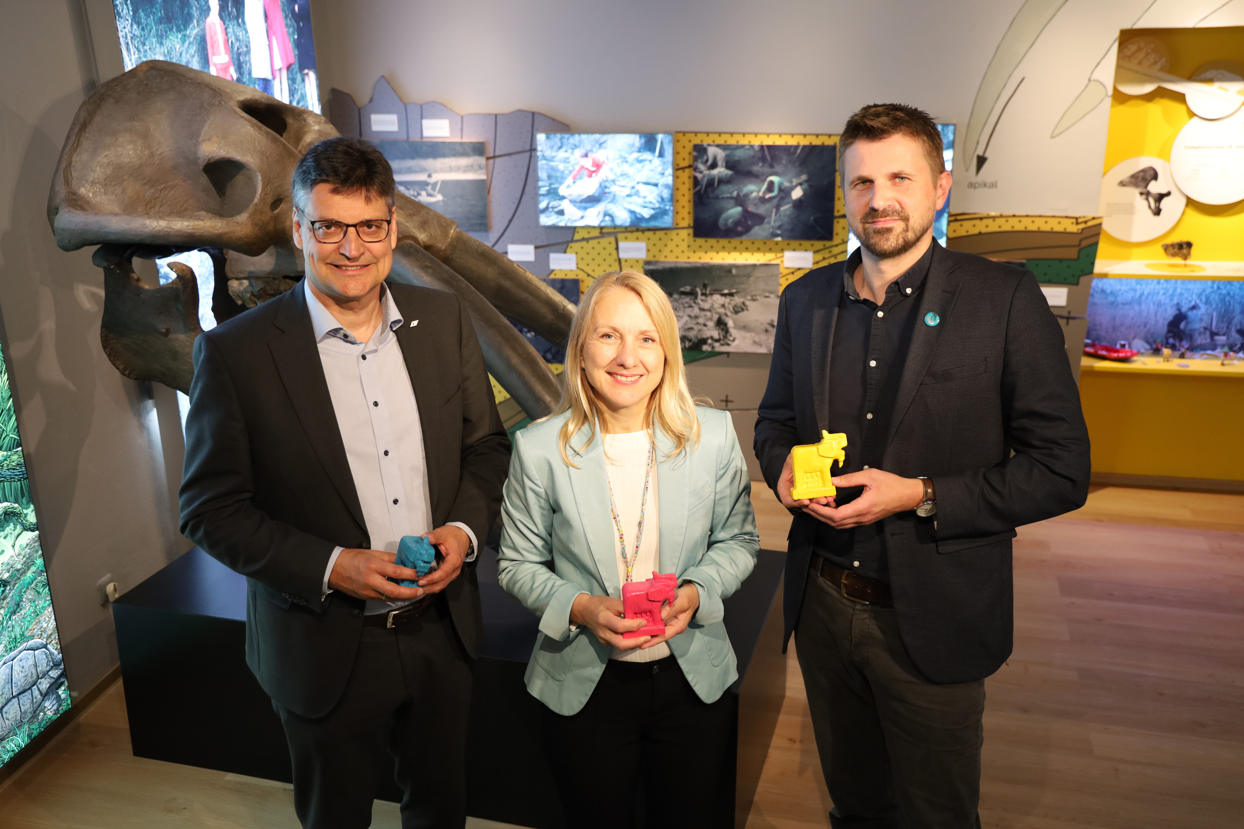 Museumsleiter Korbinian Engelmann (rechts) überreichte kleine bunte Urelefanten an Landrat Max Heimerl und Bürgermeisterin Claudia Hungerhuber.