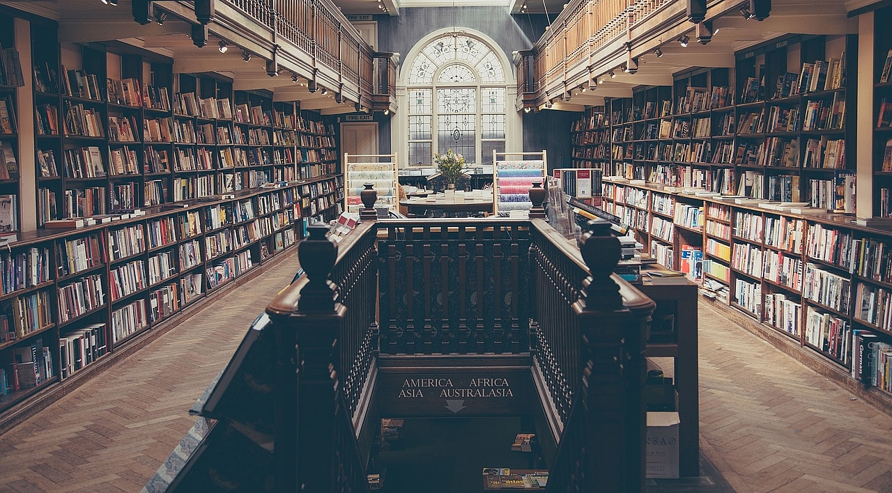 Bibliothek von innen mit vielen Büchern und einer Treppe in der Mitte 