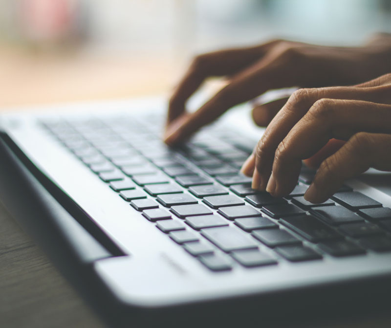 Person tippt auf einem Laptop