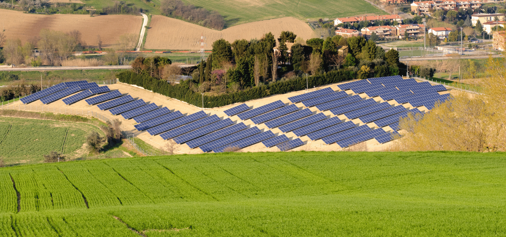 Feld mit Solaranlagen und einer Stadt im Hintergrund