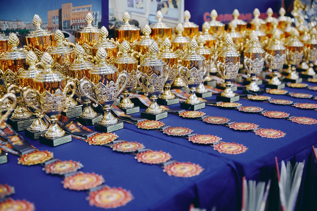 Viele Trophäen und Medaillen auf einem Tisch mit blauer Tischdecke