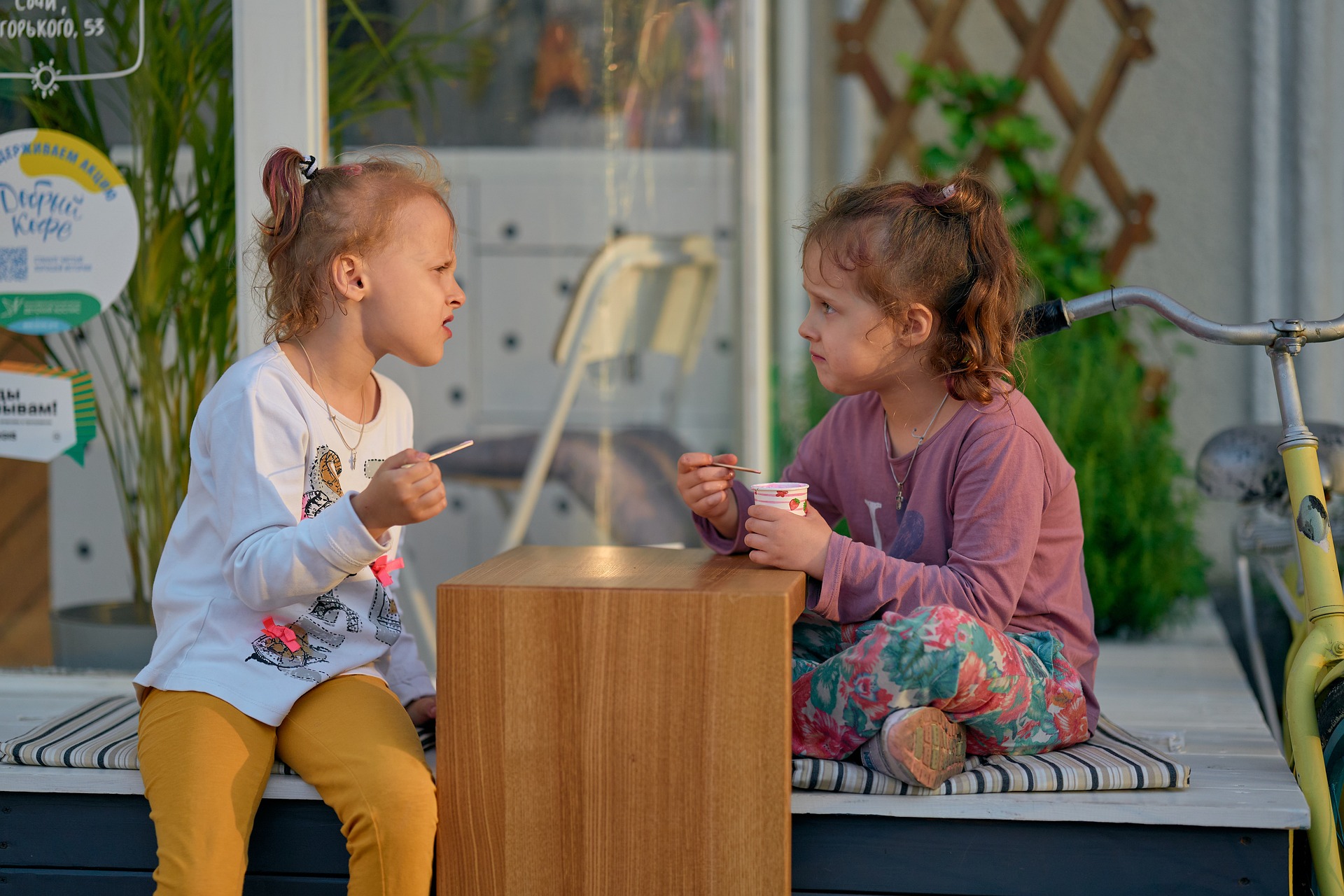 zwei Mädchen sitzen an einem Tisch und essen Eis